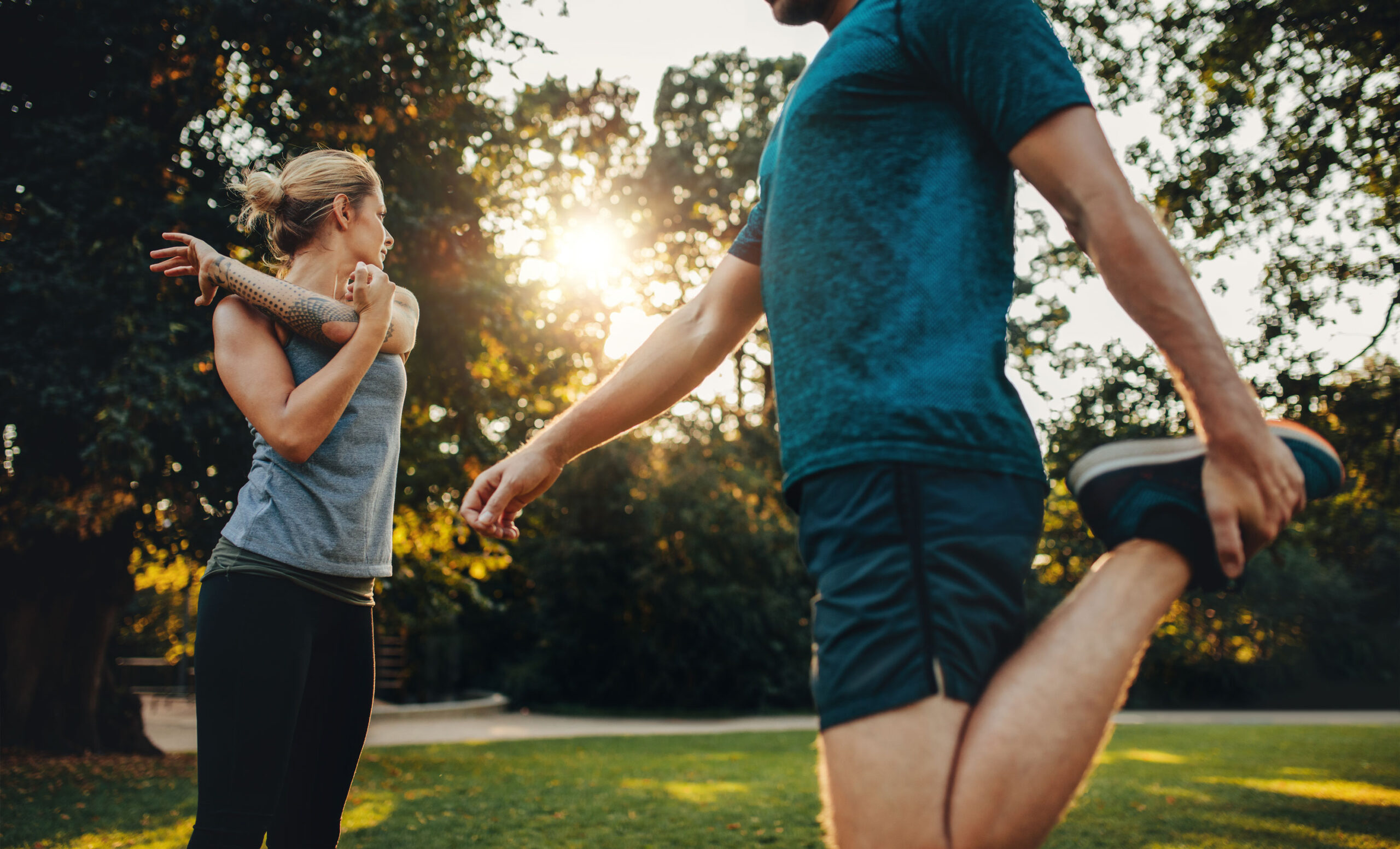 Man and woman in gym clothing stretching in the park